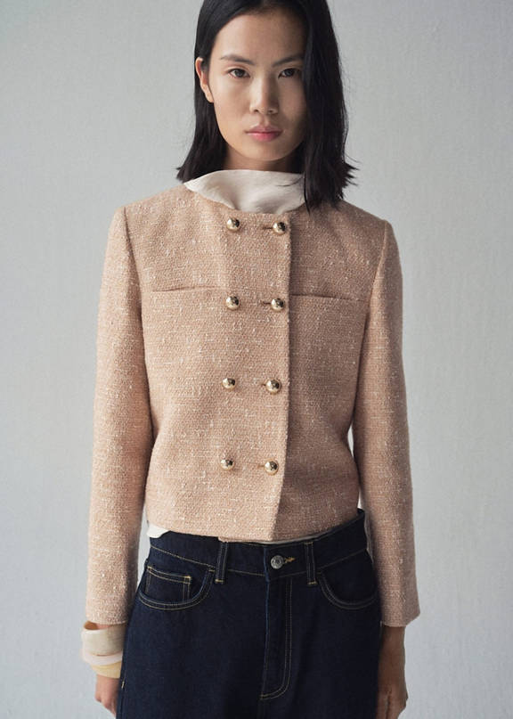 Woman wearing a woman's winter outfit with a white shirt and a tweed print jacket