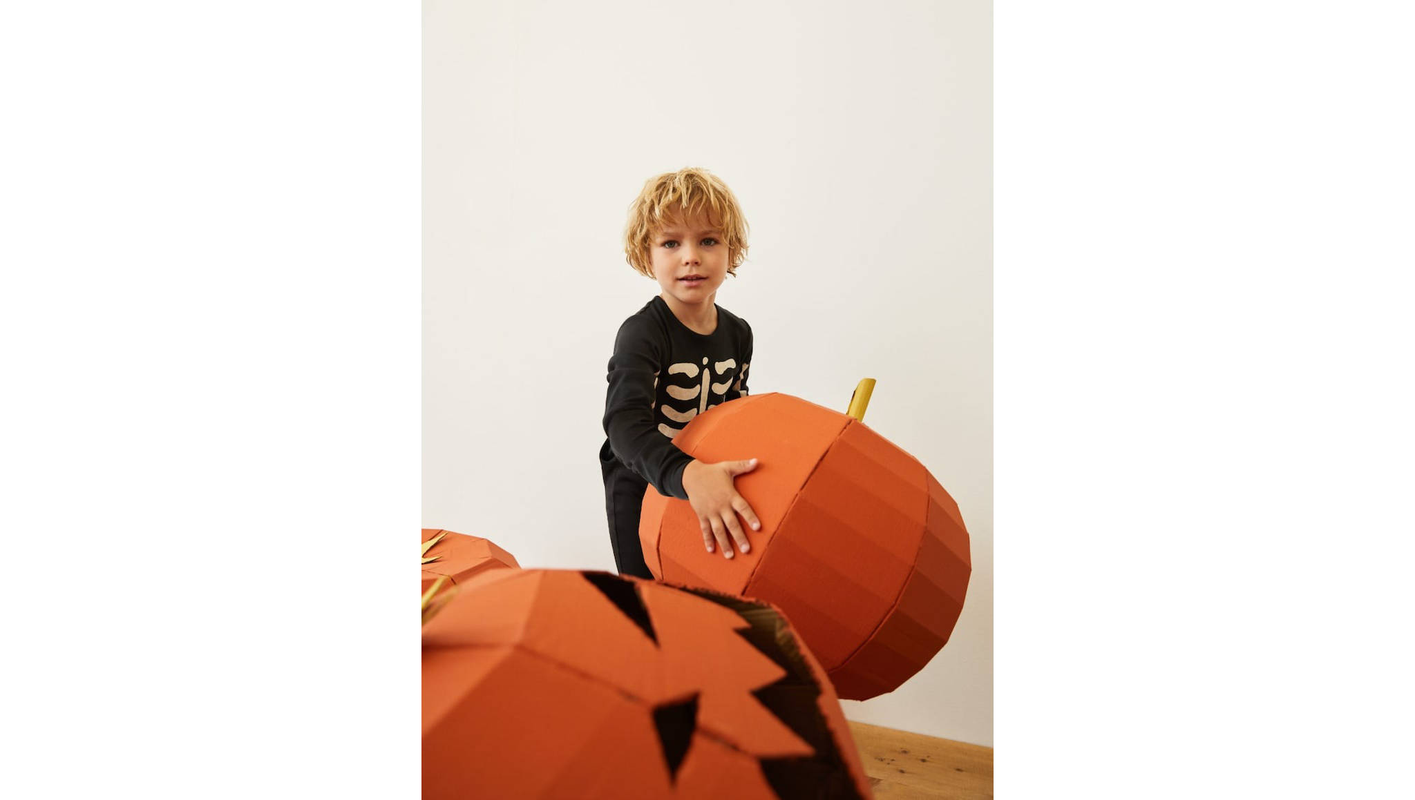A kid playing with a pumpkin